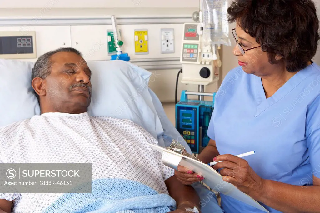 Nurse Talking To Senior Male Patient On Ward