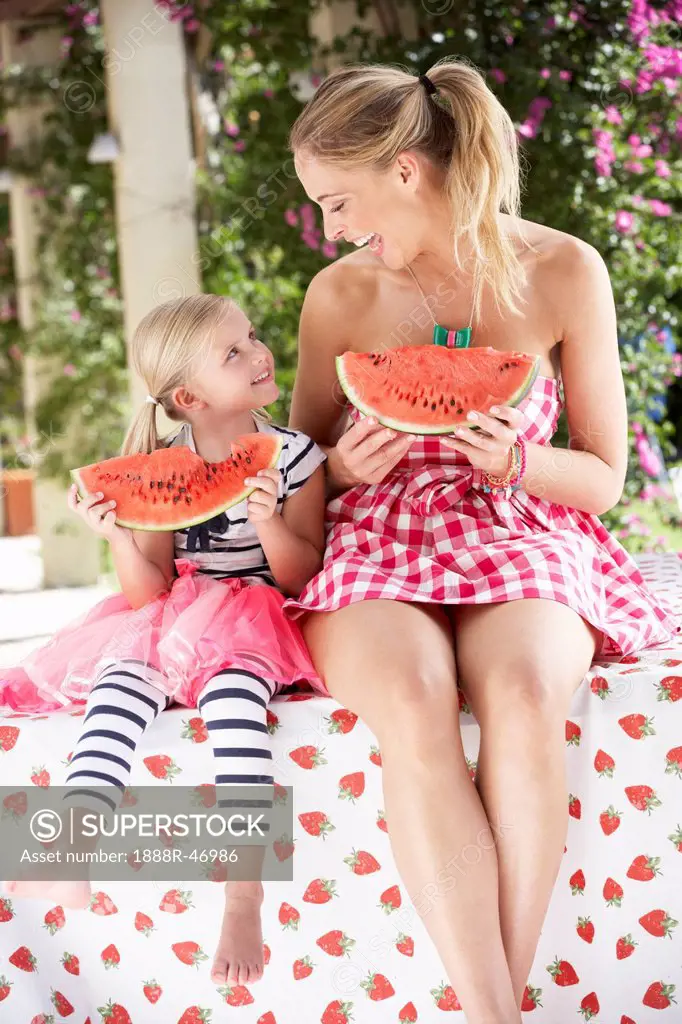 Mother And Daughter Enjoying Breakfast Cereal Outdoors Together