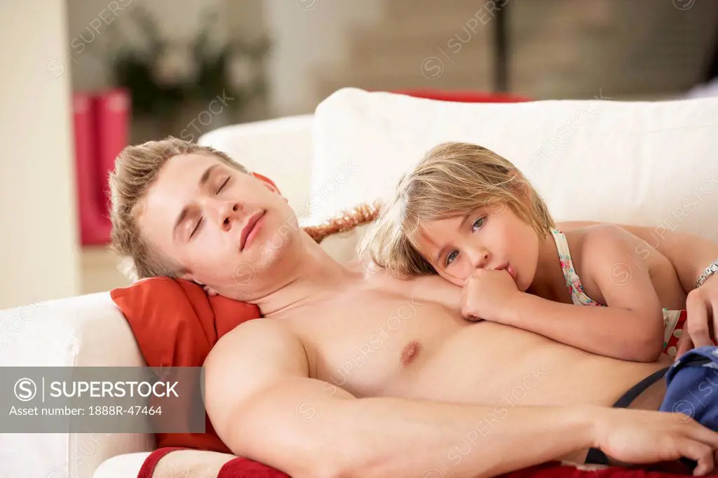 Father And Daughter Relaxing On Sofa
