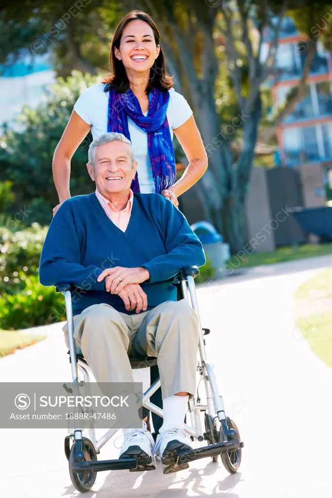 Adult Daughter Pushing Senior Father In Wheelchair