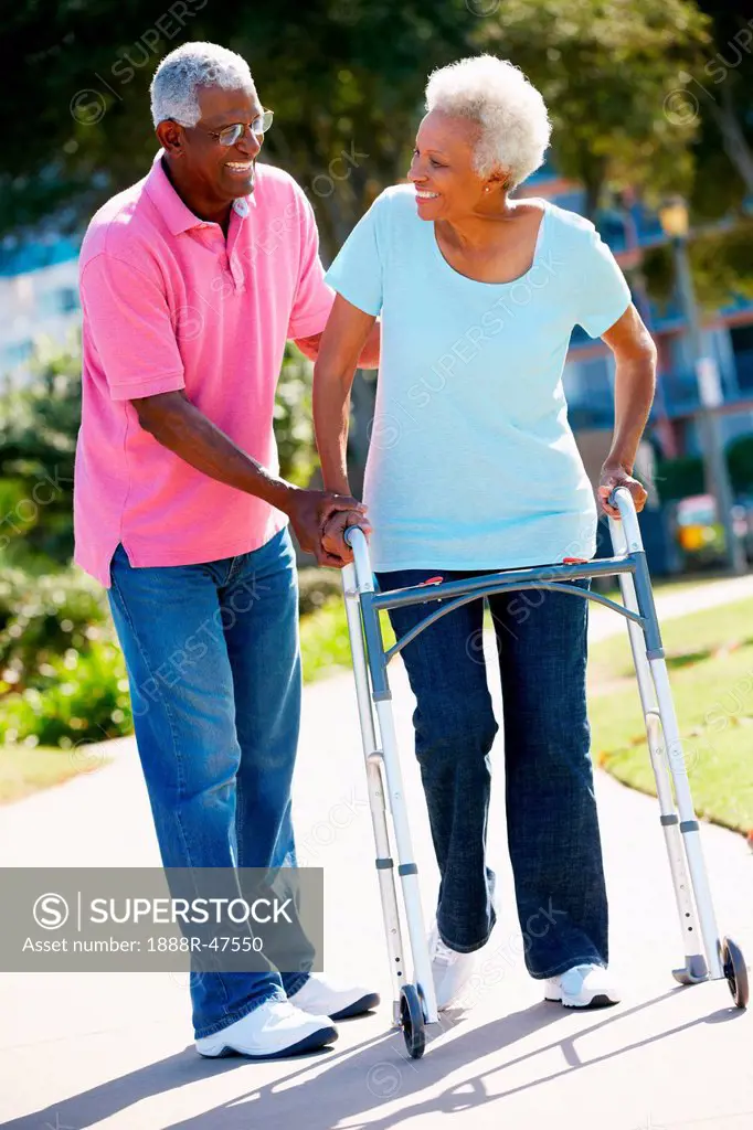 Senior Man Helping Wife With Walking Frame
