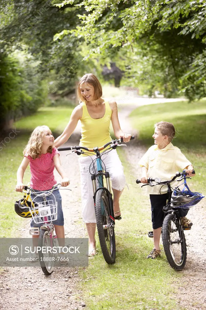 Mother and children riding bikes in countryside