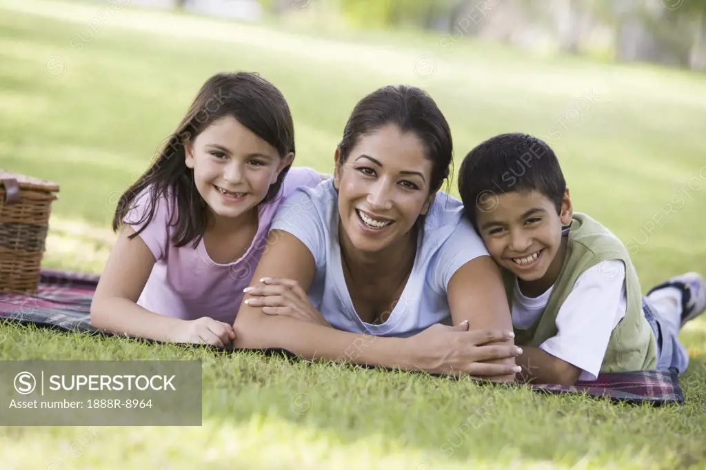 Mother and two young children outdoors in park with picnic smiling selective focus
