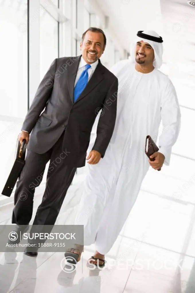 Two businessmen walking in a corridor and smiling high key/selective focus