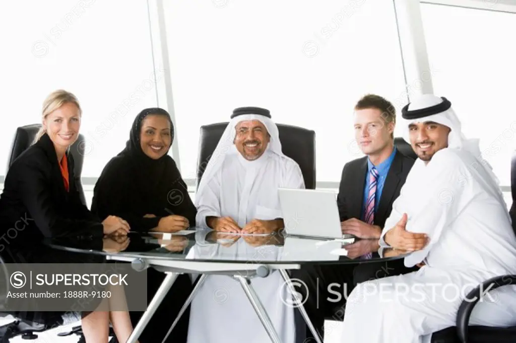 Five businesspeople in office with laptop smiling high key/selective focus