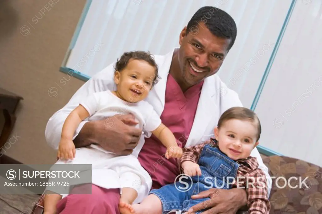 Doctor sitting with two IVF children smiling