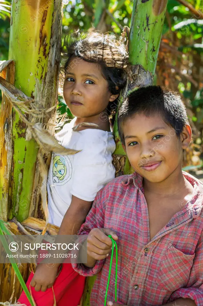 Brother and sister posing by a banana tree; Nicaragua