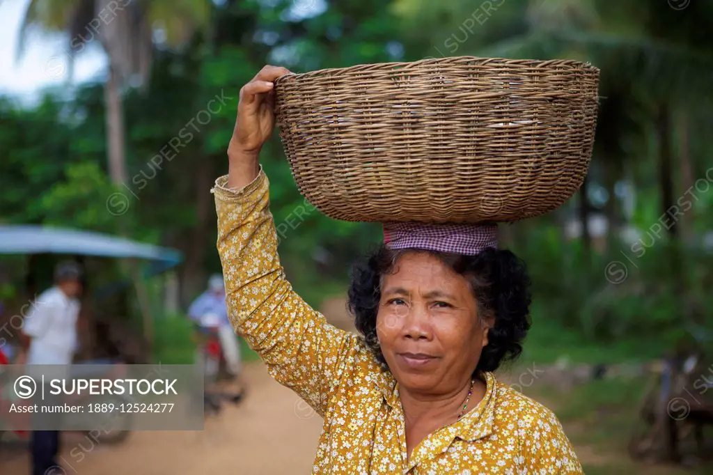 Woman carrying a basket on her head; Battambang, Cambodia
