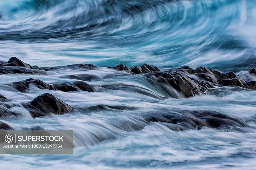 Long exposure of waves striking the coastline and flowing over rocks; Iceland