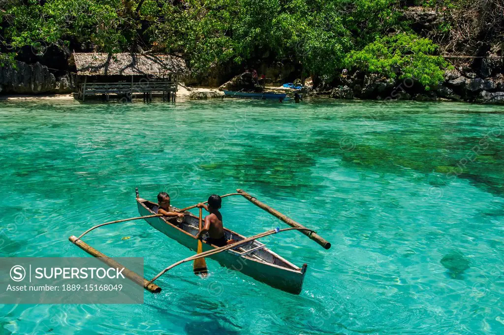 Boys paddling in an outrigger canoe, fishing in the turquoise waters of the  Indian Ocean; Andaman Islands, India - SuperStock