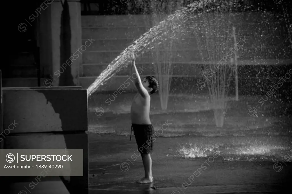 Young boy playing in fountain spray