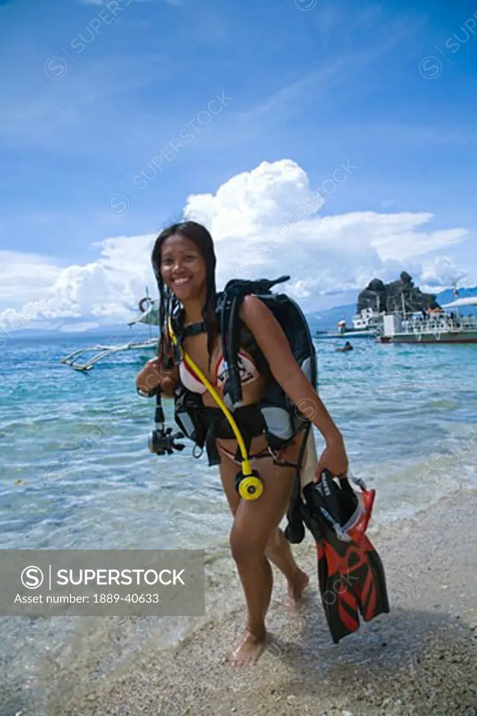 Young woman with diving equipment standing in water; Dumaguete, Oriental Negros Island, Philippines