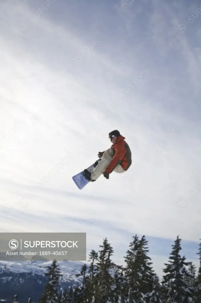 Man snowboarding, jumping in mid-air; Vancouver Island Ranges, British Columbia, Canada