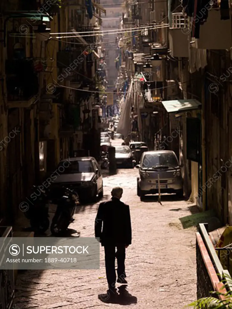 Man walking on street of historic old town, rear view; Naples, Italy