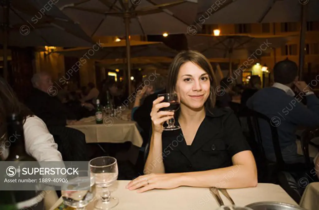 Woman smiling with glass of wine, outdoors; Roma Italy