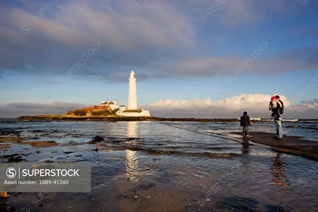 Father with two children watching lighthouse; Whitley Bay, Northumberland, England