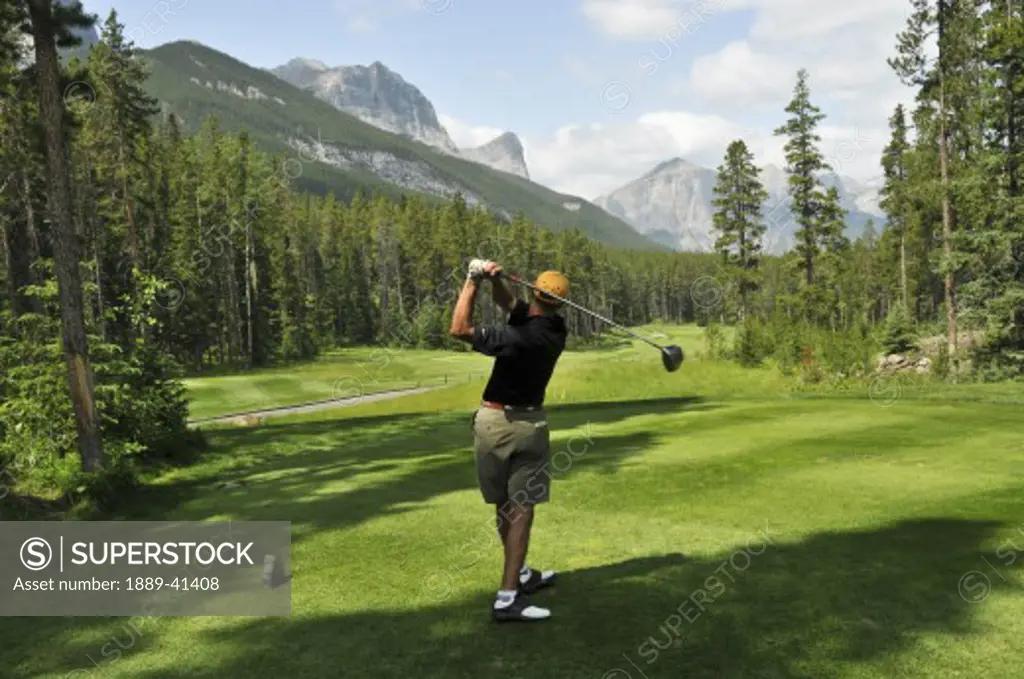 Mid-adult man playing golf; Canmore, Alberta's Rockies, Alberta, Canada