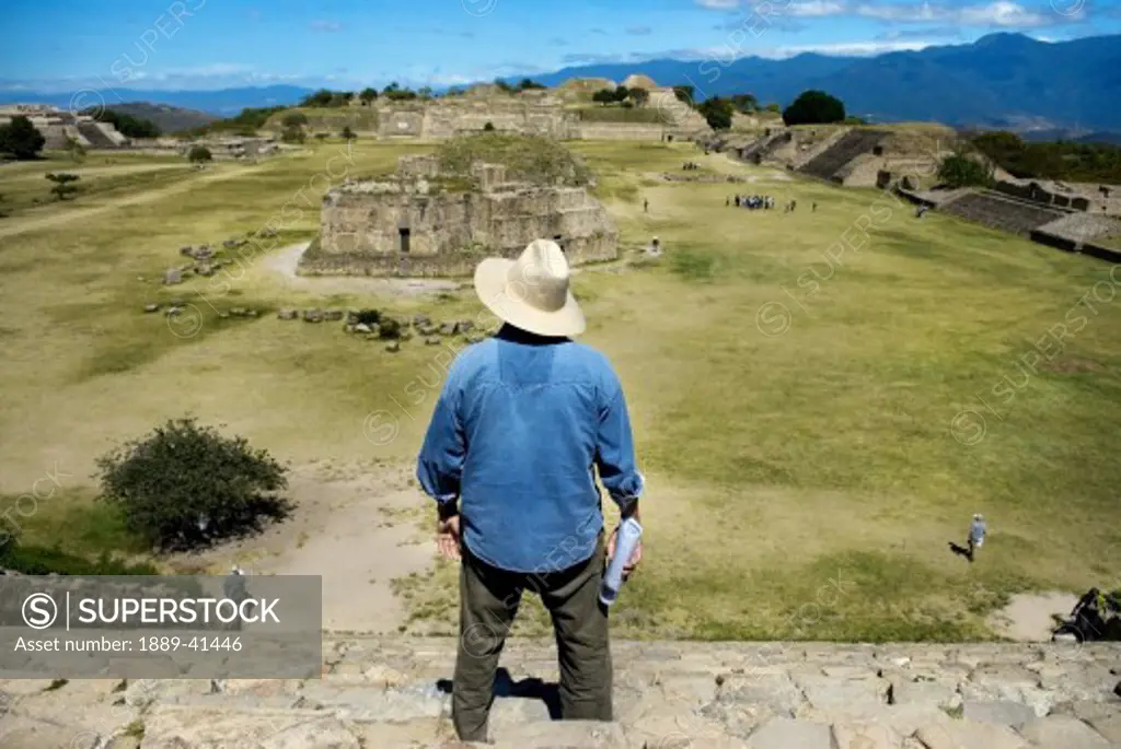 Elevated rear view of man watching ancient mayan ruins; Mexico