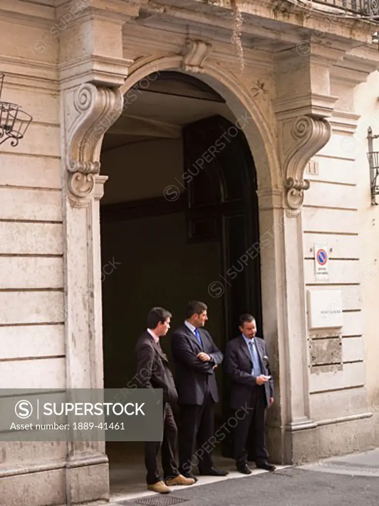 Three mid-adult men standing in entrance gate; Rome, Italy