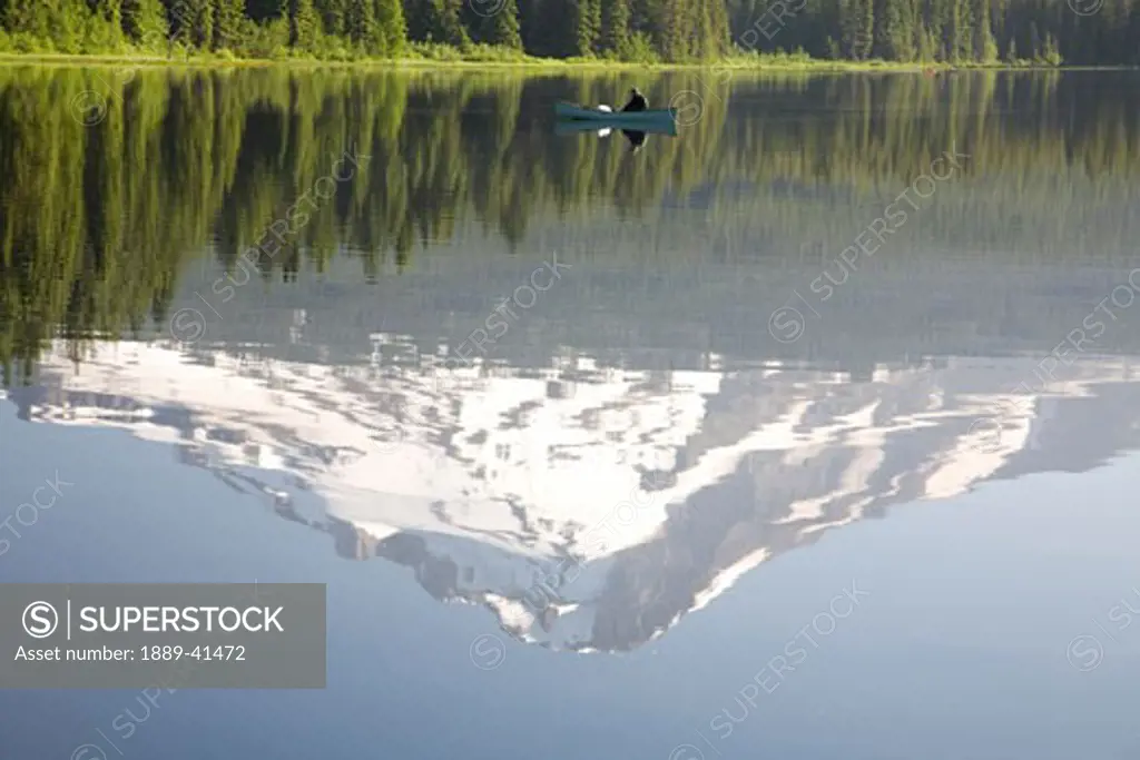 Man on boat, Mt. Hood reflects in Trillium Lake; Mt Hood National Forest, Oregon, USA