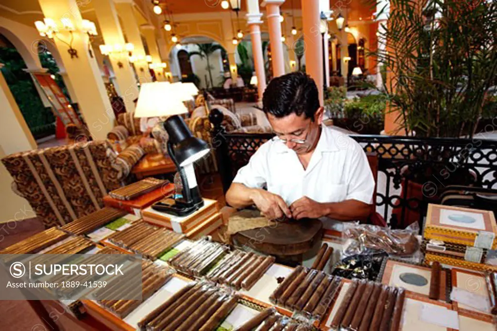 Cigar maker rolling cigars; 