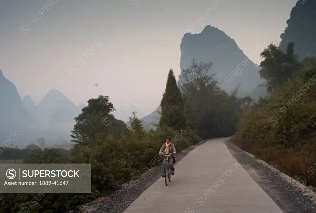 Young woman riding bike in mountain area; 