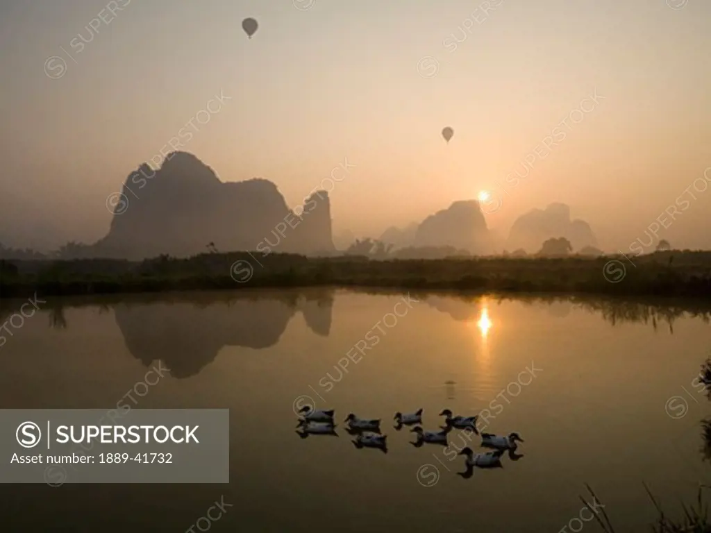 Ducks on mountain lake at sunset; 