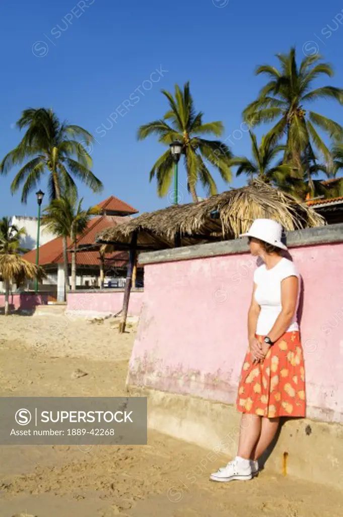 Santa Cruz Beach, Huatulco, Oaxaca State, Mexico; Woman leaning on wall on beach