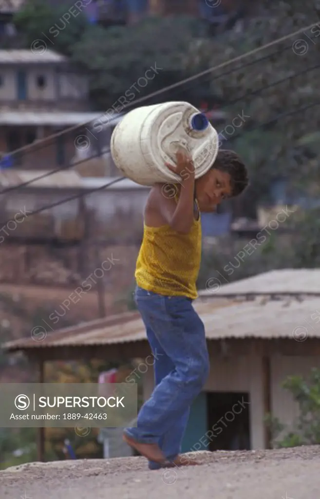 Boy carrying container on shoulders