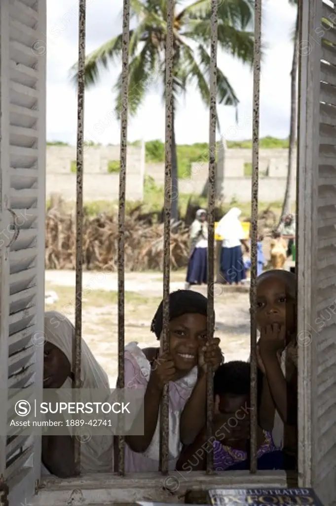 Zanzibar, Tanzania; Children looking through barred window