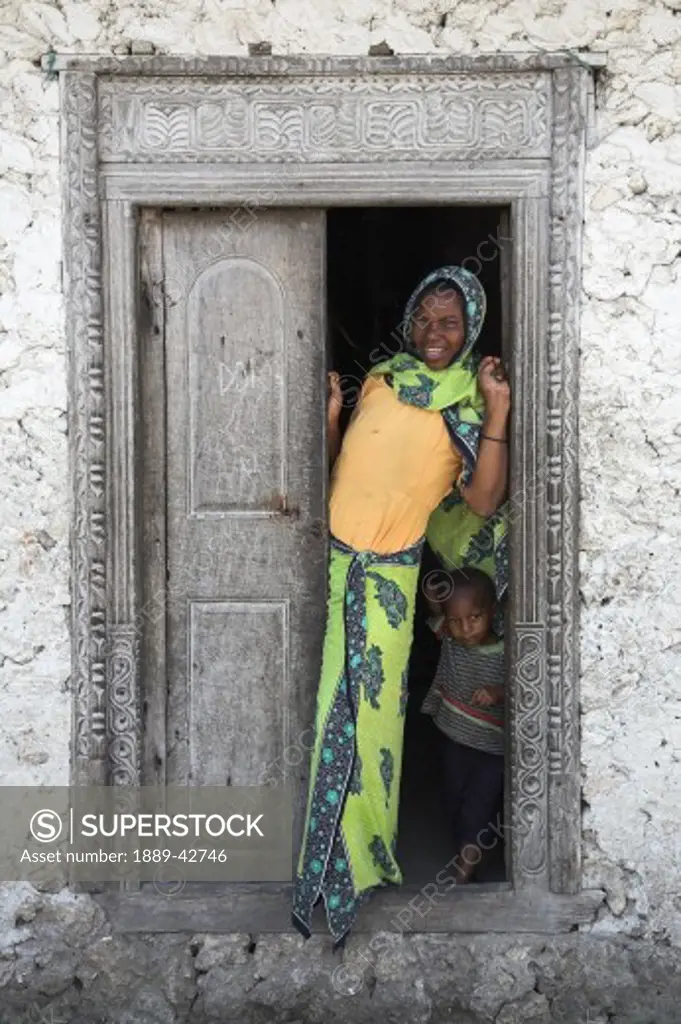 Pwani Mchangani, Zanzibar, Tanzania; Mother and son standing in doorway