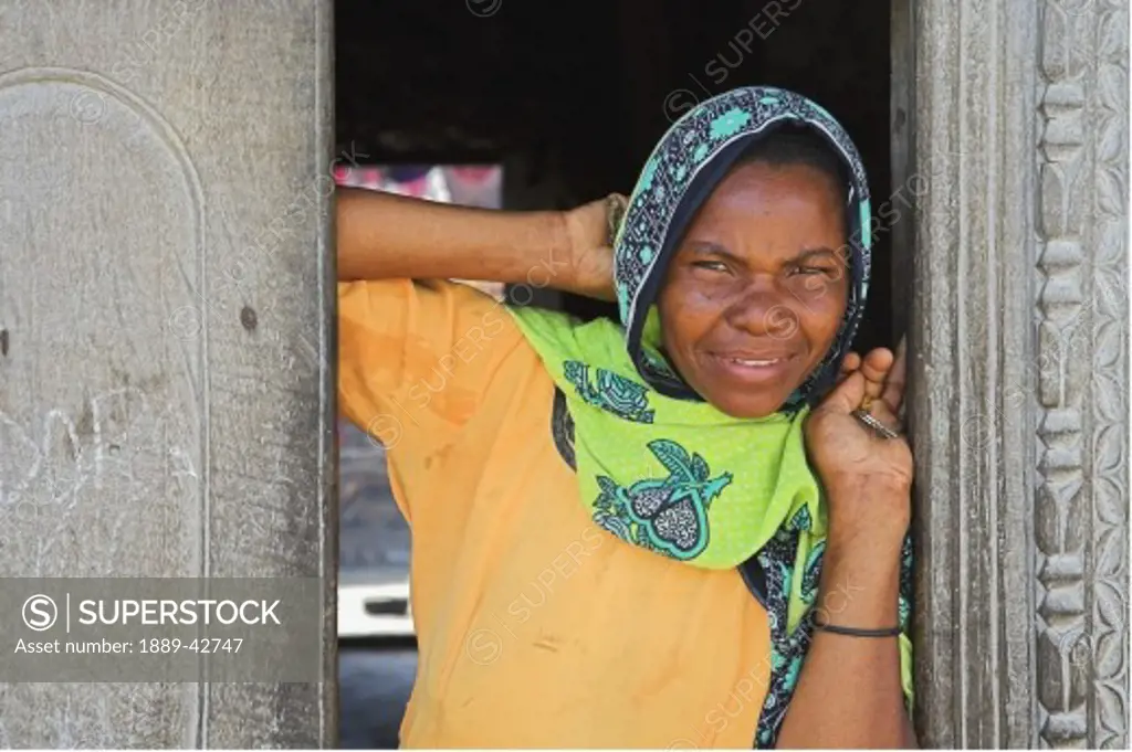 Pwani Mchangani, Zanzibar, Tanzania; Woman leaning in doorway