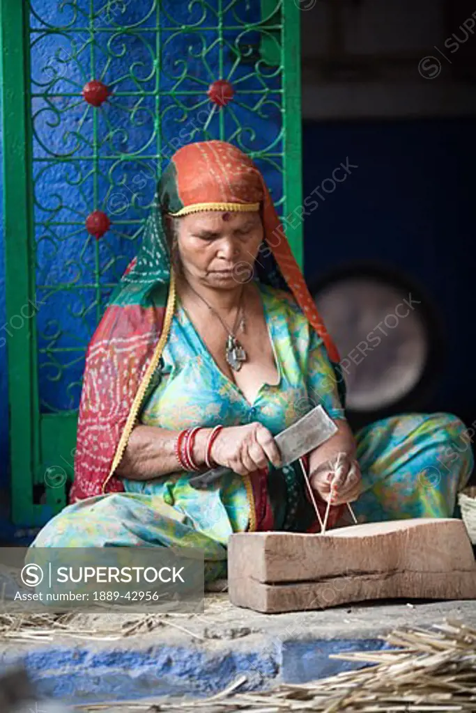 Jodhpur, India; Woman in sari sitting in house cutting