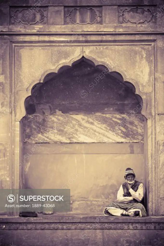 Delhi, India; Man sitting under architectural arch