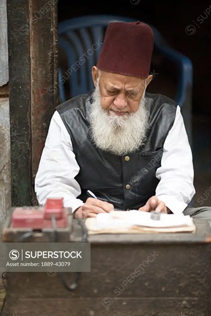 Delhi, India; Man writing in notebook