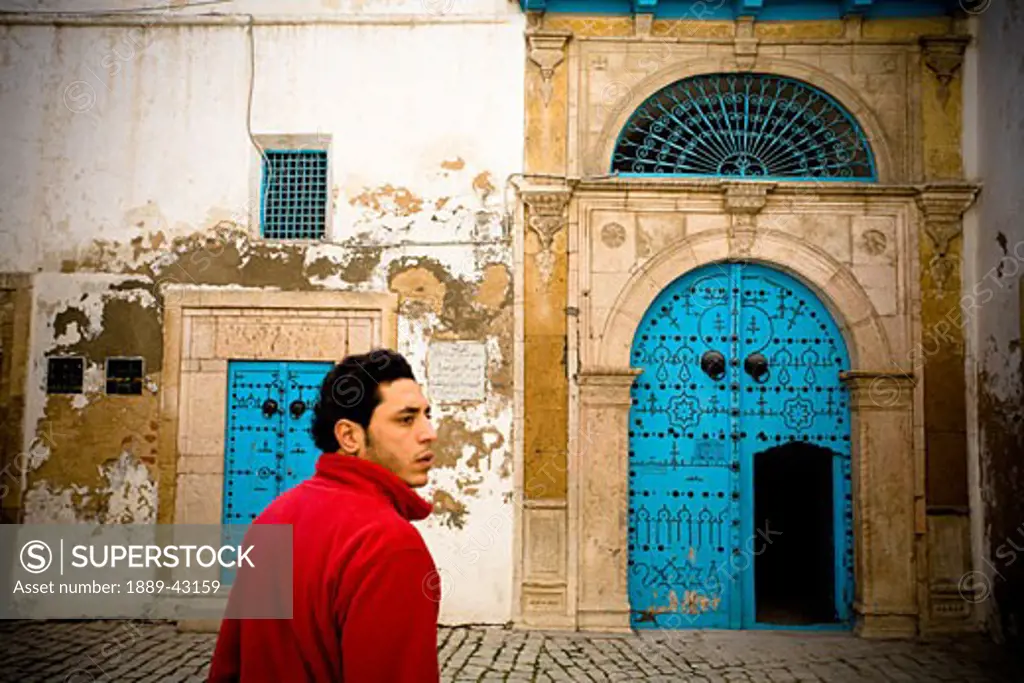 Tunis, Tunisia; Man walking towards weathered building