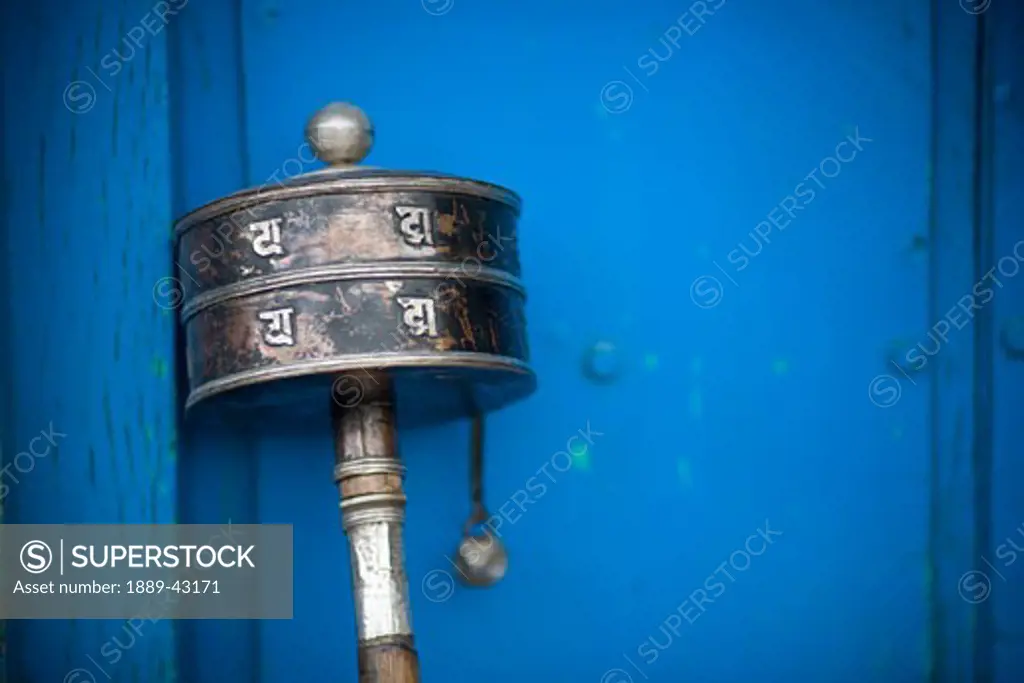 Boudhanath, Kathmandu, Nepal; Prayer wheel leaning against building