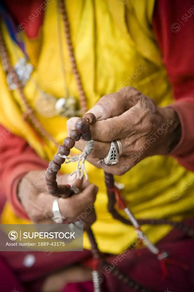 Boudhanath, Kathmandu, Nepal; Buddhist monk holding prayer beads