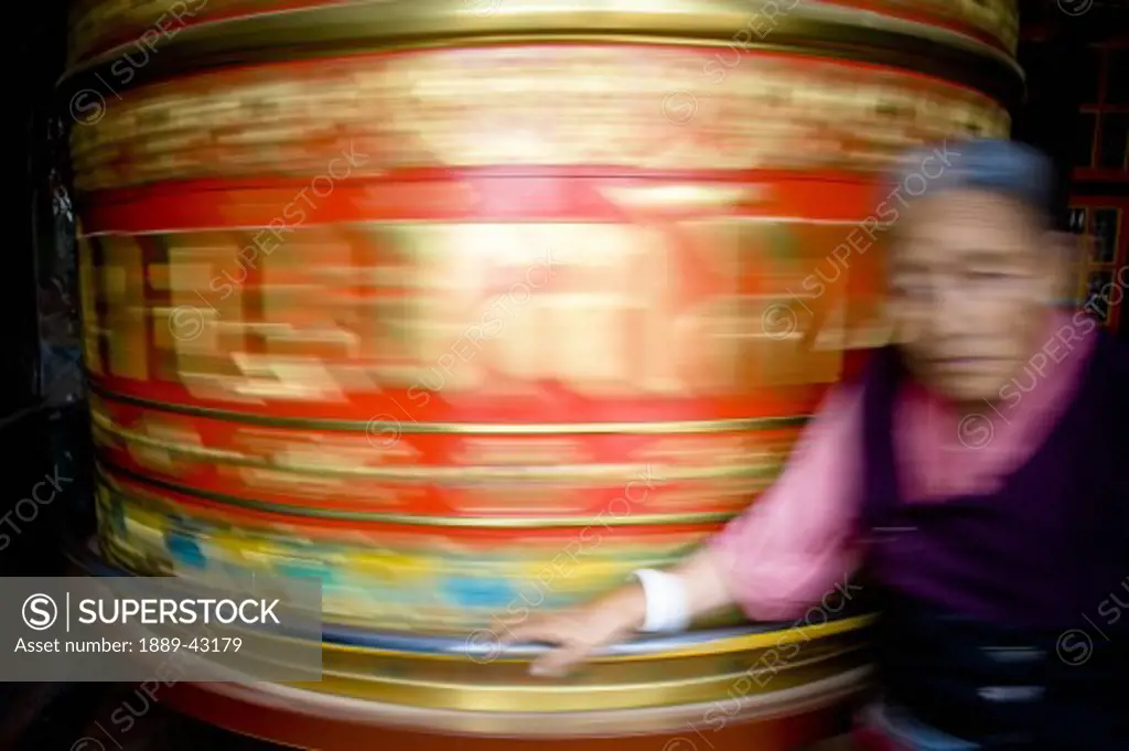 Boudhanath, Kathmandu, Nepal; Woman spinning mani wheel