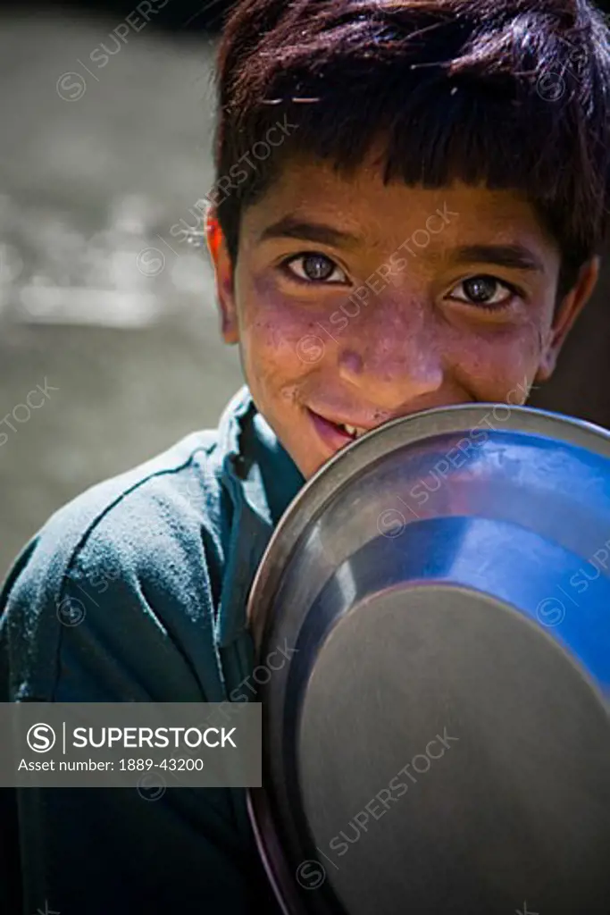 Lidderwat, Kashmir, India; Boy with metal plate looking at camera