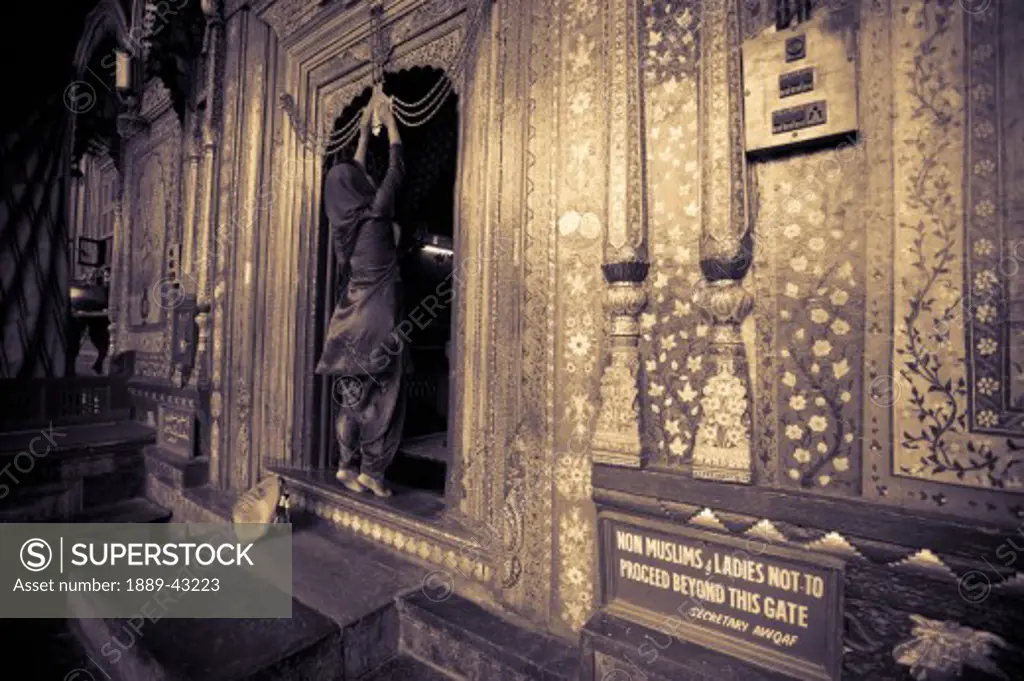 Dal Lake, Srinagar, Kashmir, India; Woman standing in doorway to shrine