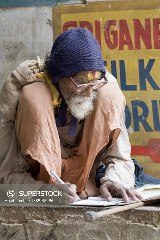 Ganges River, Varanasi, India; Old man writing in journal