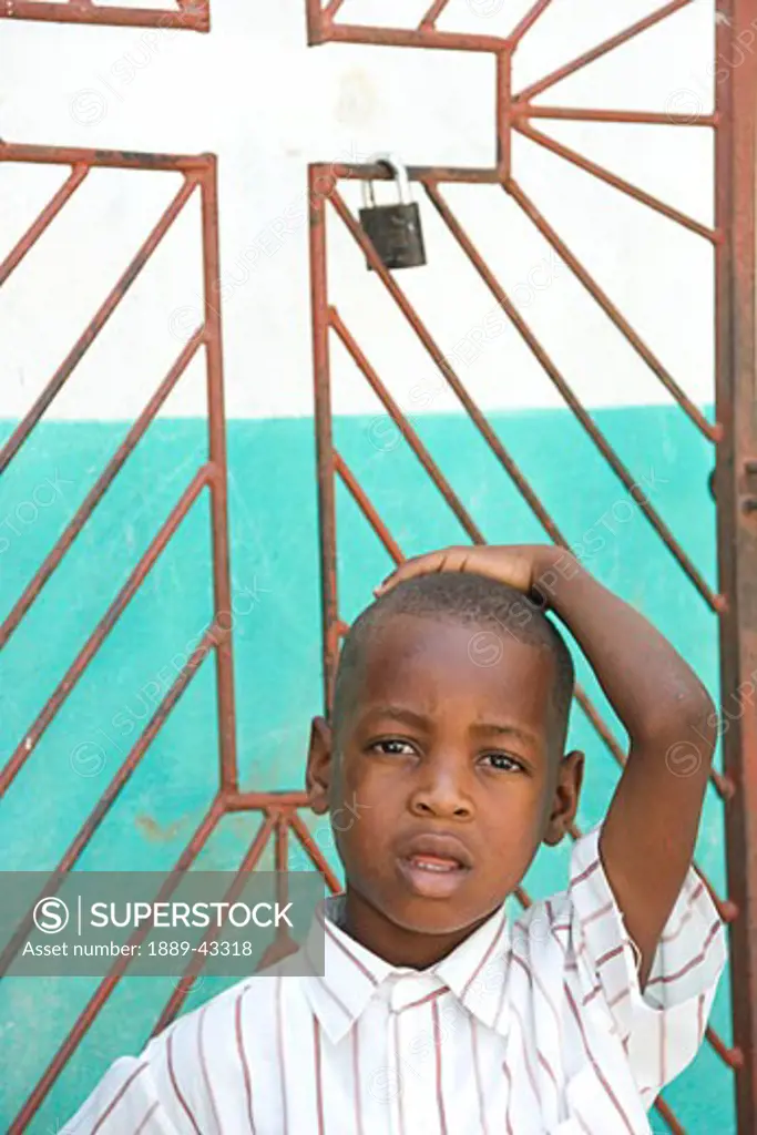 Haiti; Young boy standing in front of church gate