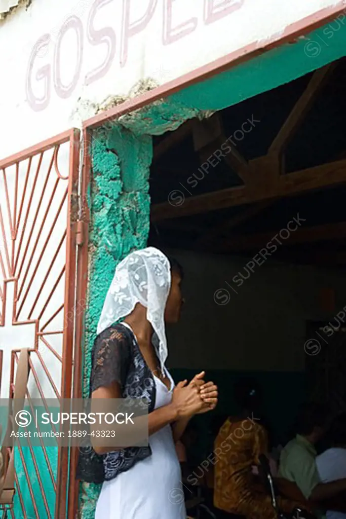 Haiti; Young woman standing in front of church door