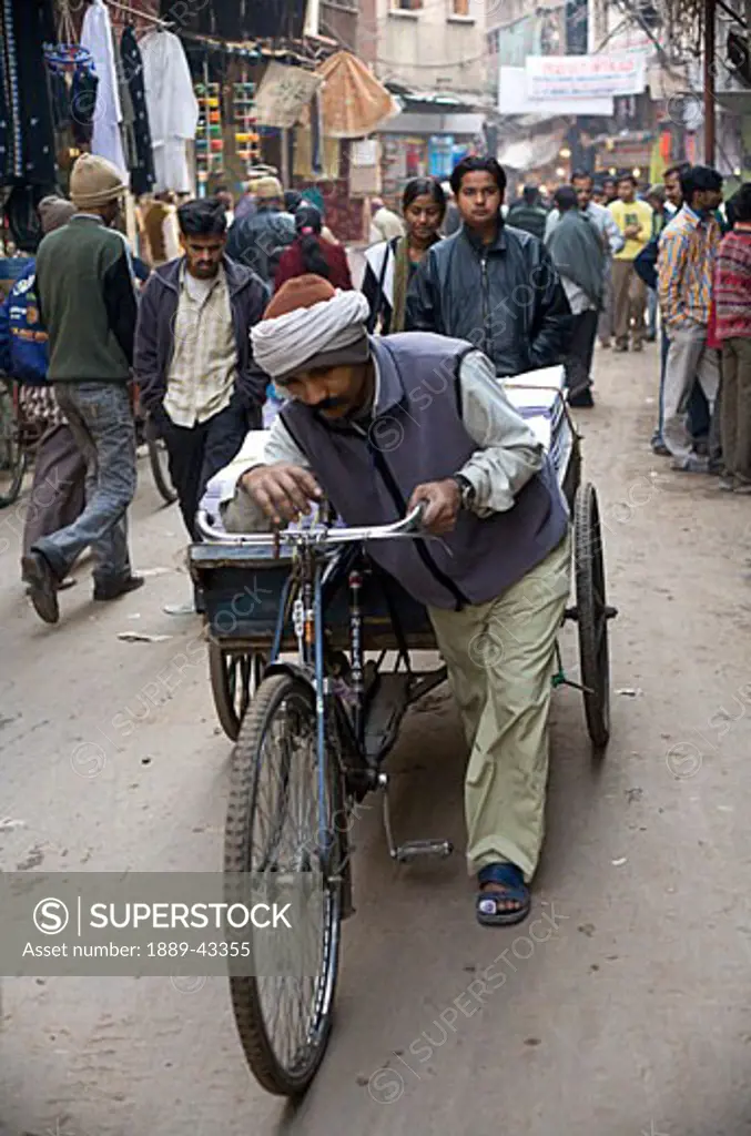 Old Delhi, India; Man pushing a bike down the street