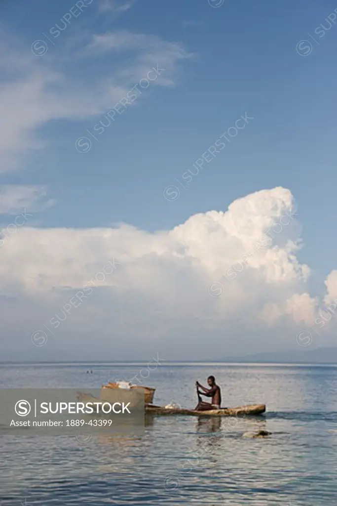 Haiti; Man paddling canoe with baskets