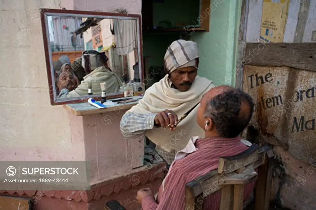 Ganges River, Varanasi, India; Barber shaving customer