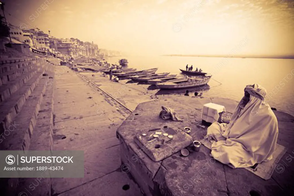 Varanasi, Uttar Pradesh, India; Man sitting on rock at the edge of river