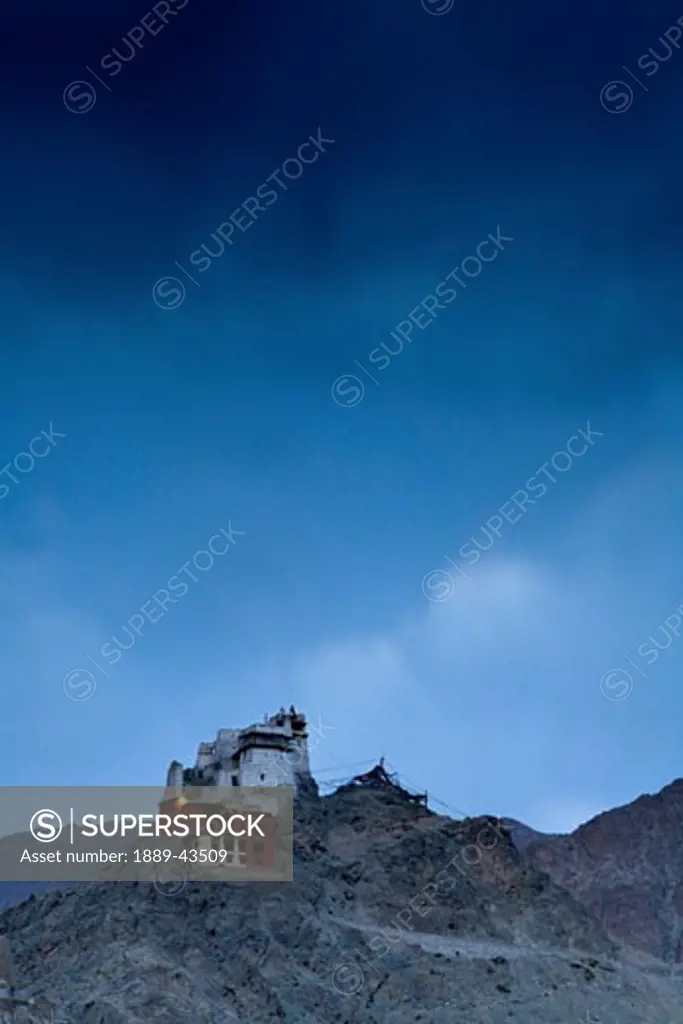 Ladakh, India; Lone building sitting atop rugged mountain range