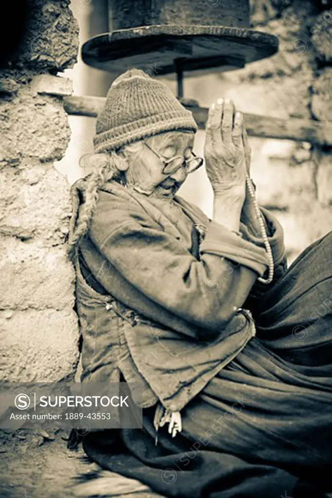 Lamayuru Monastery, Ladakh, India; Local woman sitting outside monastery praying
